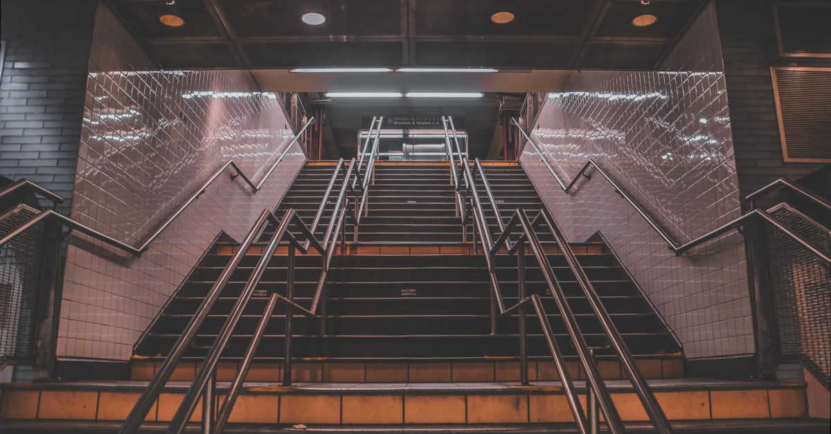 Wide-angle view of a subway station staircase in NYC, featuring modern design.